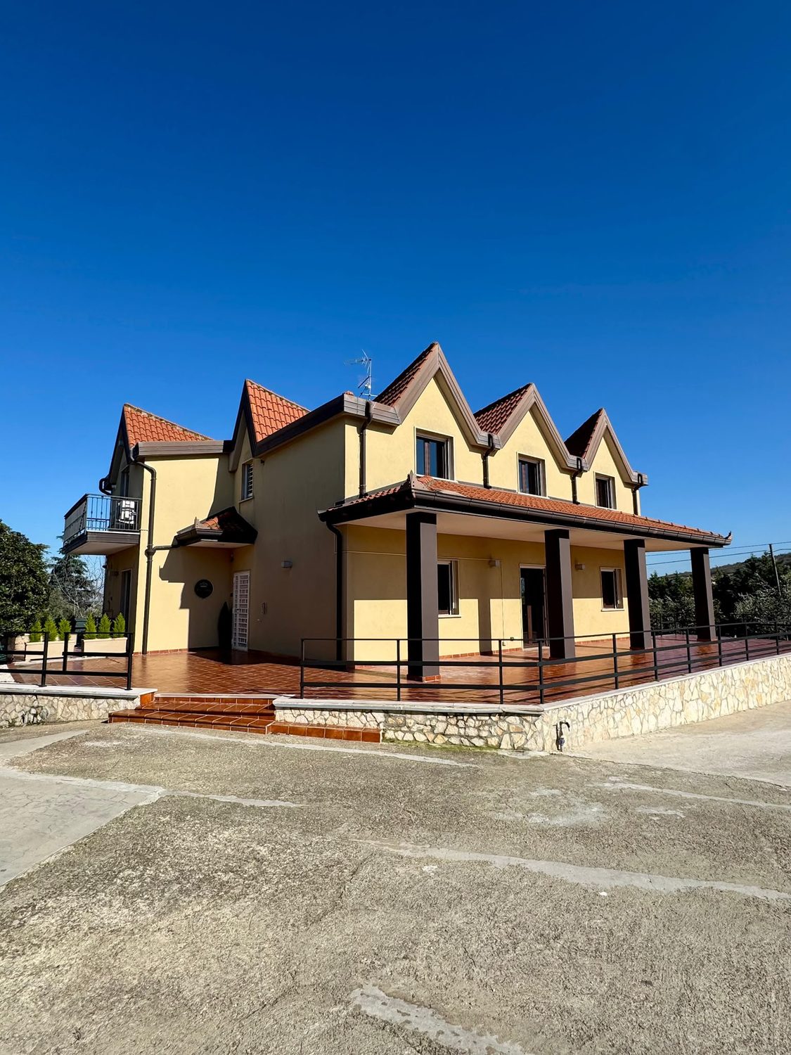 Villa Vittoria Relais, edificio giallo con tetti a punta in coppi rossi, veranda su pilastri scuri e piazzale davanti