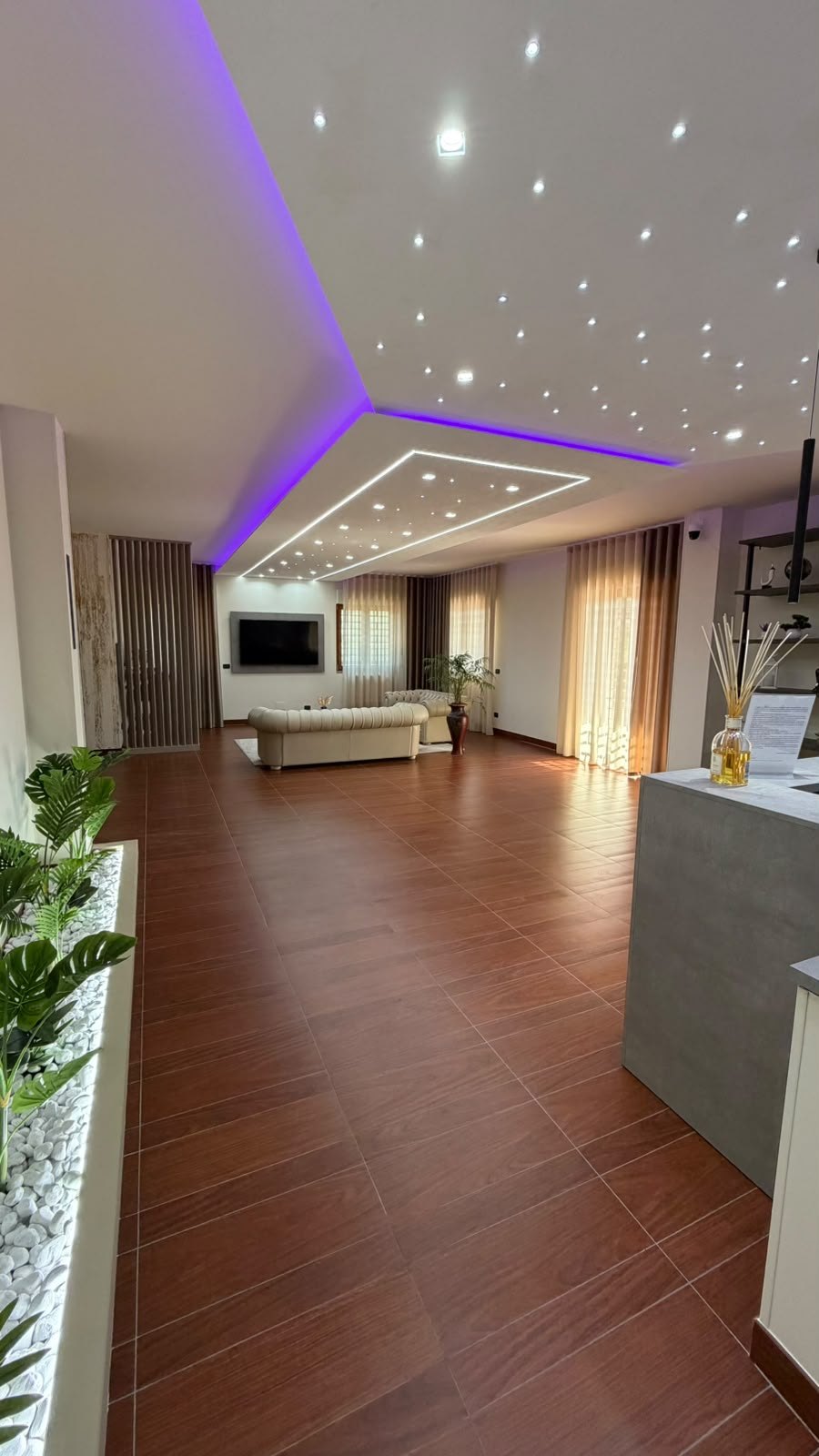 Hall di Villa Vittoria Relais con pavimento effetto legno, divano chesterfield beige, faretti e luci LED viola a soffitto